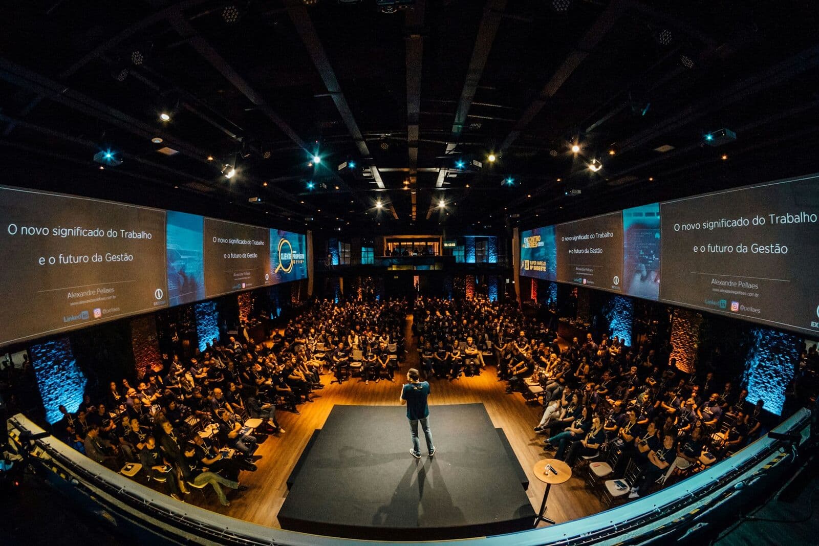 Auditorio lleno durante una conferencia con pantallas a los costados del escenario